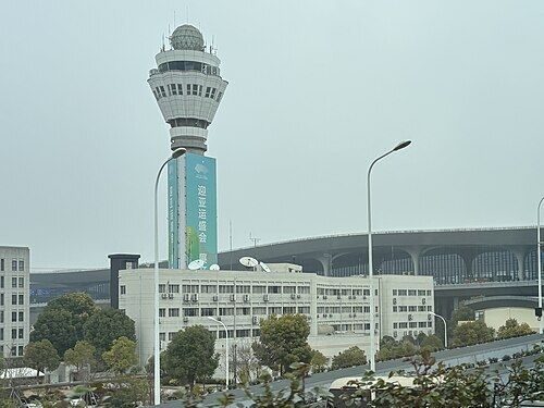 Context: the CAAC East China ATC Bureau Zhejiang Branch building and tower at Hangzhou Xiaoshan airport, March 2024. This unit runs Hangzhou tower, approach and area control; its head Wang Jian said in 2010 that 'no conclusion has yet been drawn'.